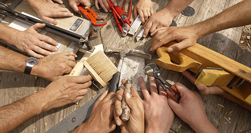 Handwerker verschiedener Gewerke gemeinsam an einem Werktisch
